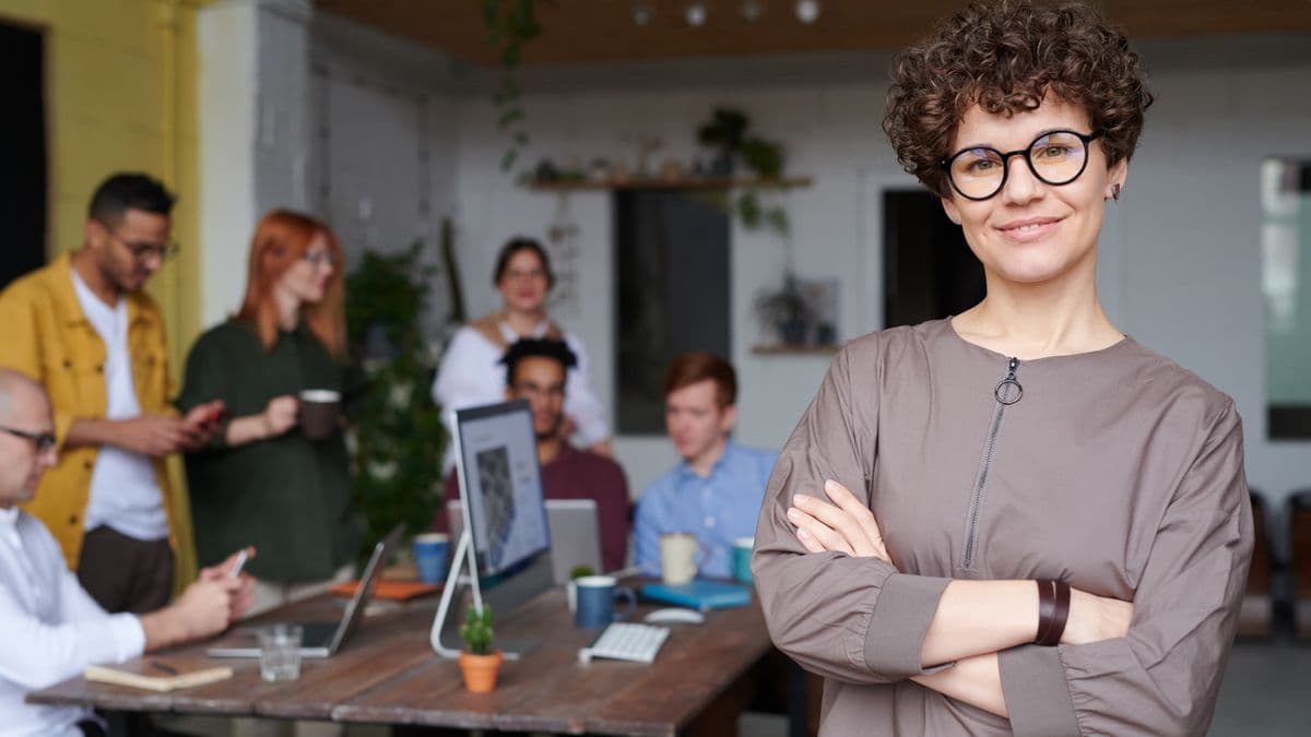 Gestionnaire souriante devant une équipe au travail, illustrant une gestion de colocation organisée