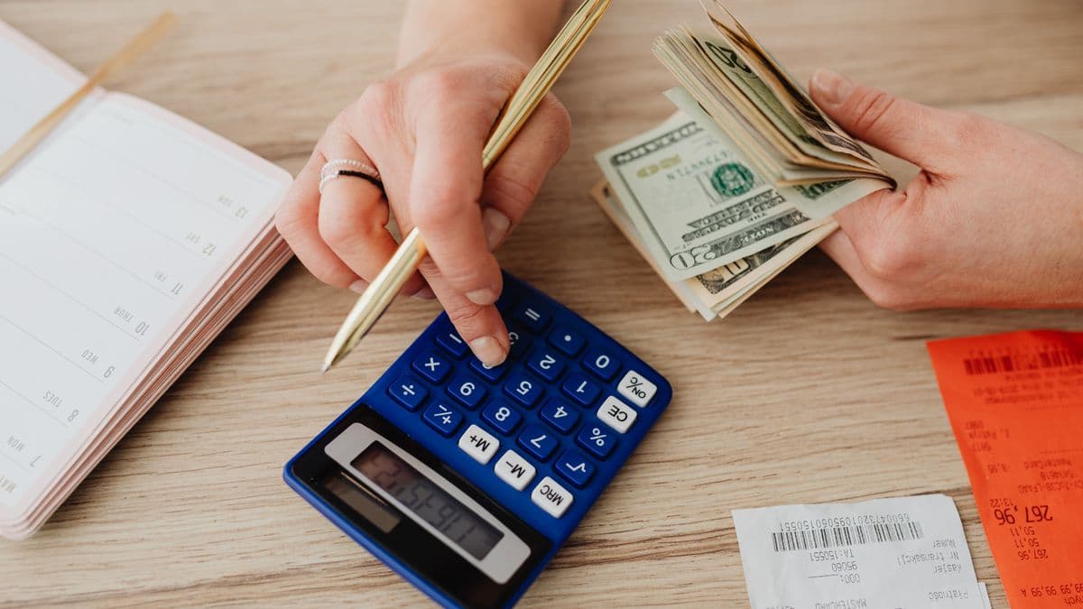 Calculatrice, billets et quittances posés sur un bureau pour suivre les loyers encaissés