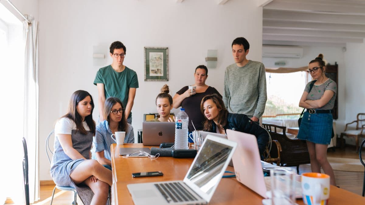 Groupe de jeunes colocataires réunis autour d'une table dans le salon d'une colocation